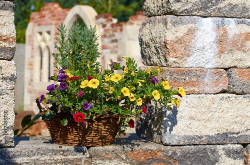 Dekorativer Blumenkorb auf Setzsteinmauer