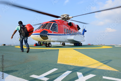 passenger carry his baggage to embark helicopter at oil rig plat
