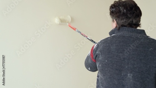 Woman colourer paints the wall using a paint roller photo
