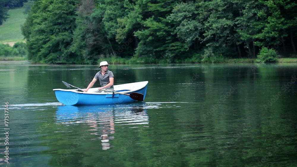 Young man in a boat preparing for fishing in a beautiful nature Young man in a boat preparing for fishing in a beautiful nature
