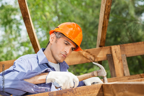 Worker Hammering Nail On Wooden Cabin