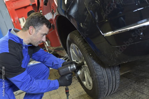 Mechanician changing car wheel in auto repair shop