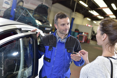 Auto repair mechanic giving car keys back to customer photo