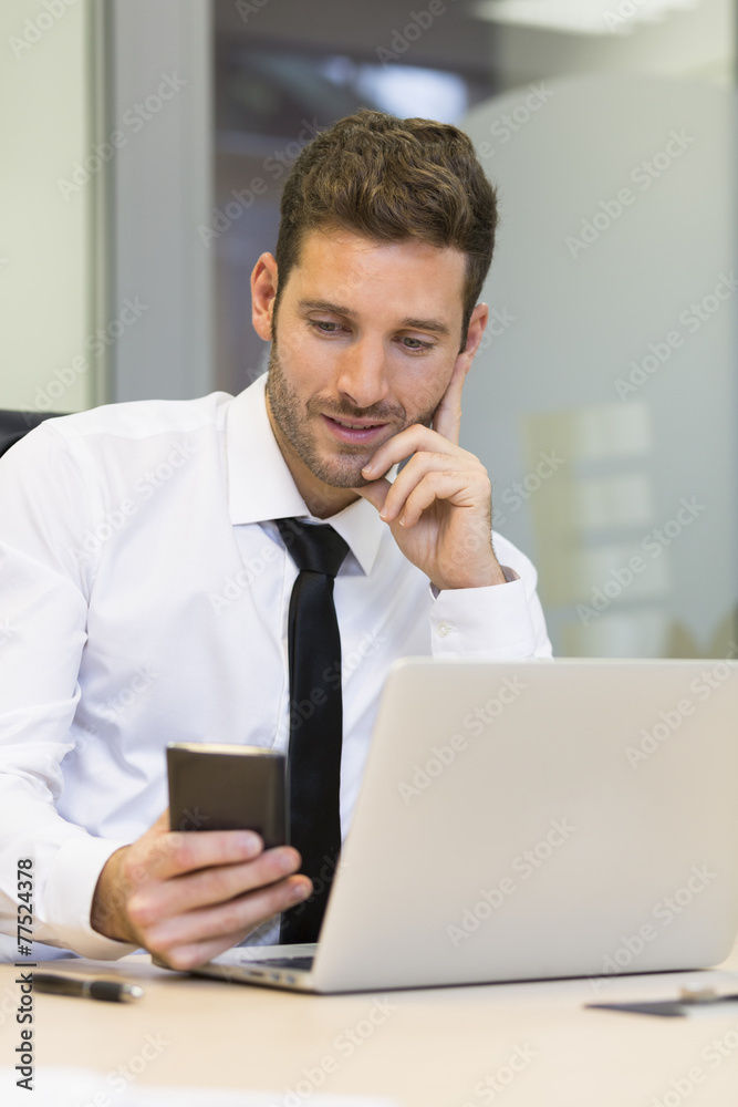 Businessman typing a message on mobile phone in office Businessman typing a message on mobile phone in office