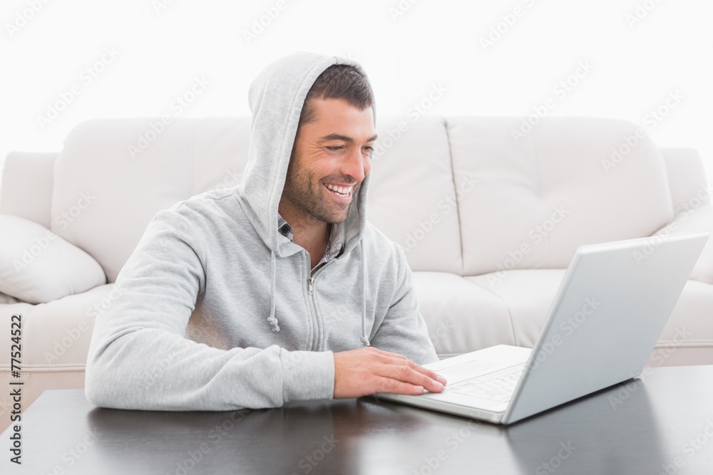 A smiling man using laptop at a table A smiling man using laptop at a table