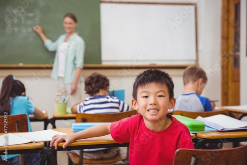 Cute pupil smiling at camera in classroom