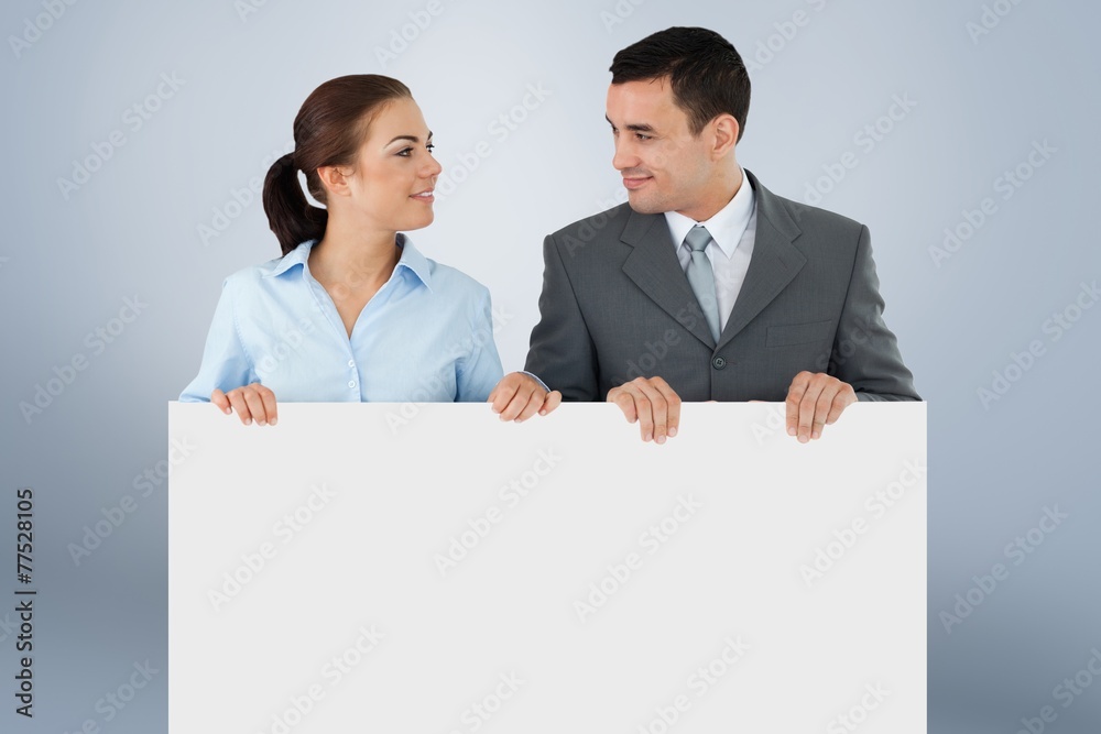 Business partners looking at each other while holding sign Business partners looking at each other while holding sign
