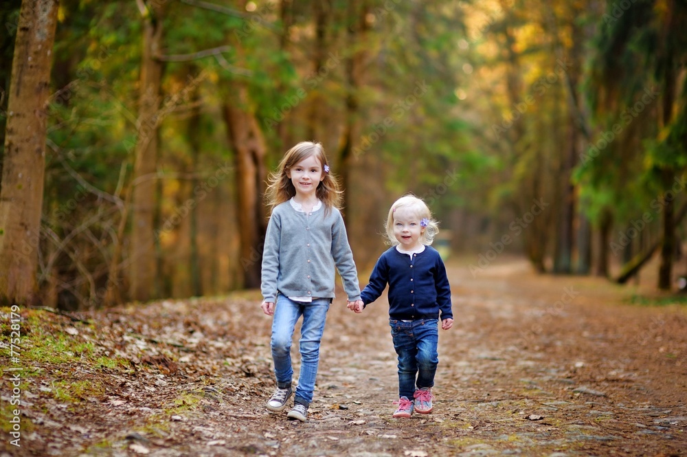 Two little sisters having fun in the woods