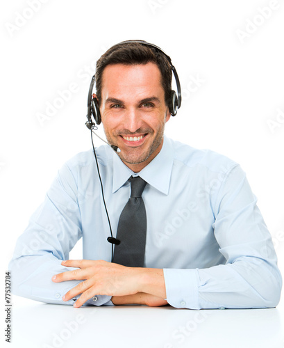 smiling man with headset leaning on his desk