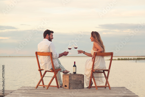 couple drinking red wine at the seaside on a jetty photo