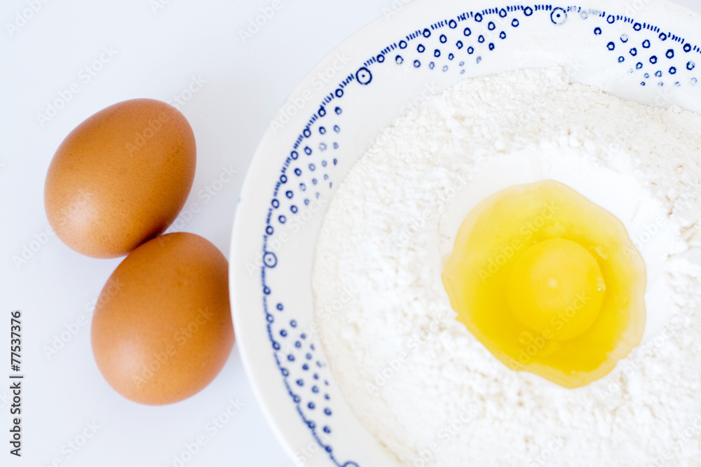 Plate with flour, eggs lying on a white background Plate with flour, eggs lying on a white background