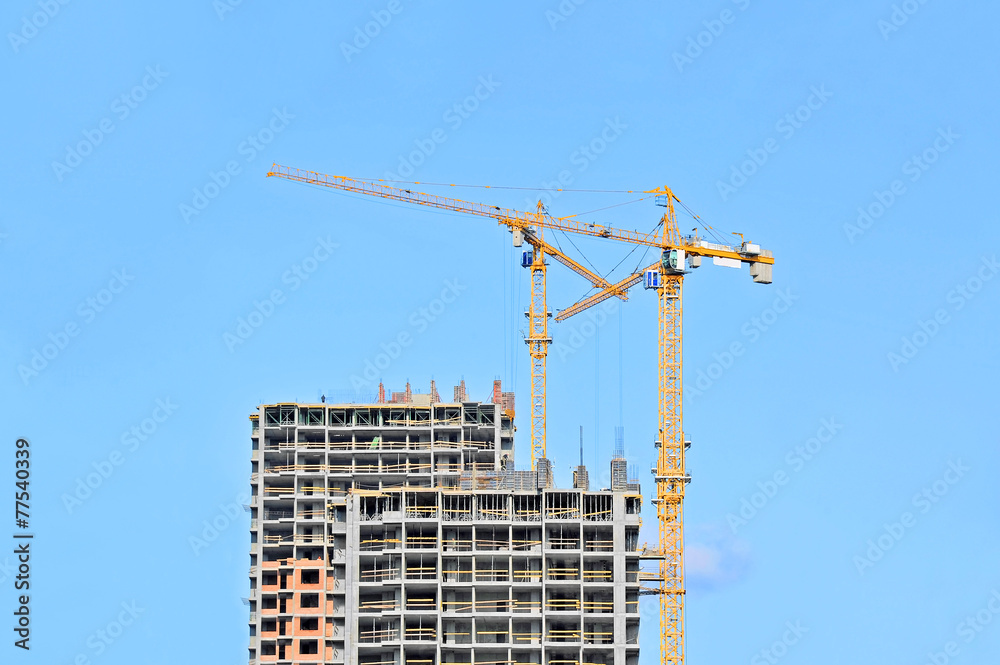 Crane and building construction site against blue sky Crane and building construction site against blue sky