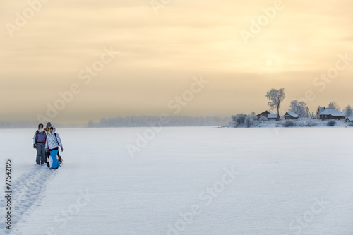 Family standing on ice of frozen lake while hiking to home © Kekyalyaynen