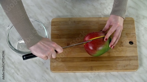 Top view of slicing mango in half on wooden desk photo