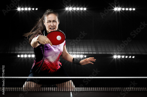 Young sports woman tennis-player in play on black background