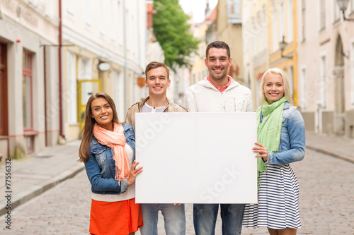 group of smiling friends with blank white board © Syda Productions