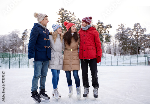 happy friends ice skating on rink outdoors