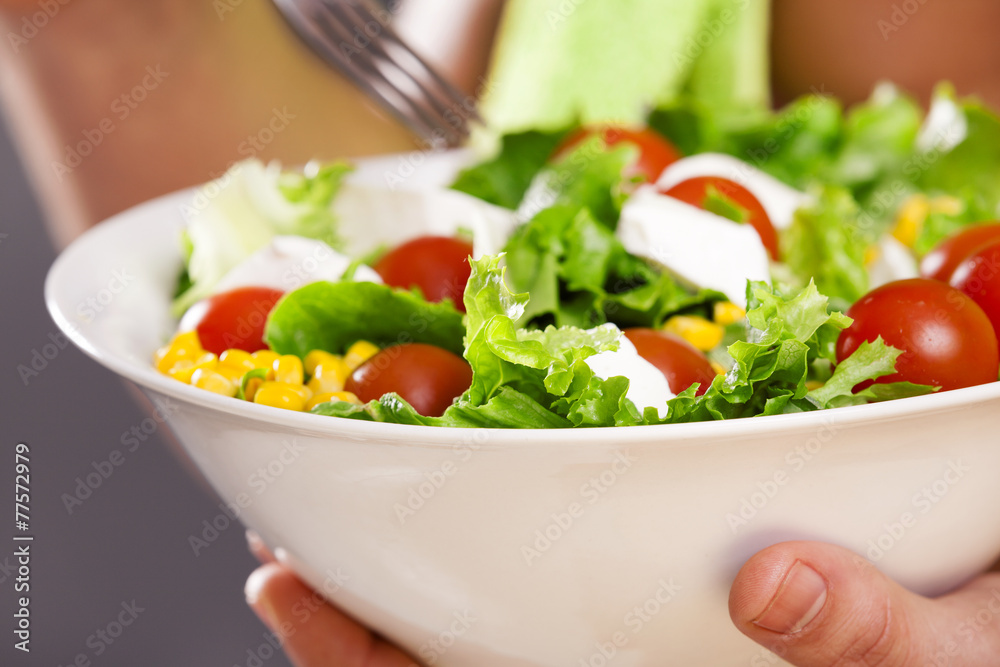 Fit man holding a bowl of fresh salad on grey background Fit man holding a bowl of fresh salad on grey background