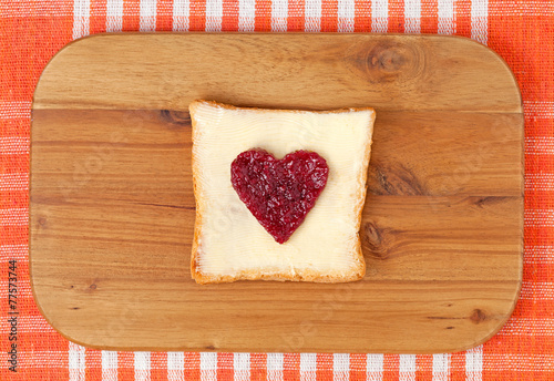 Slice of wholewheat toast with red jam in the shape of heart