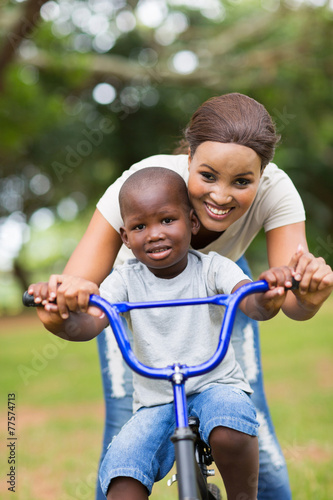 african mother teaching her little son to ride a bike