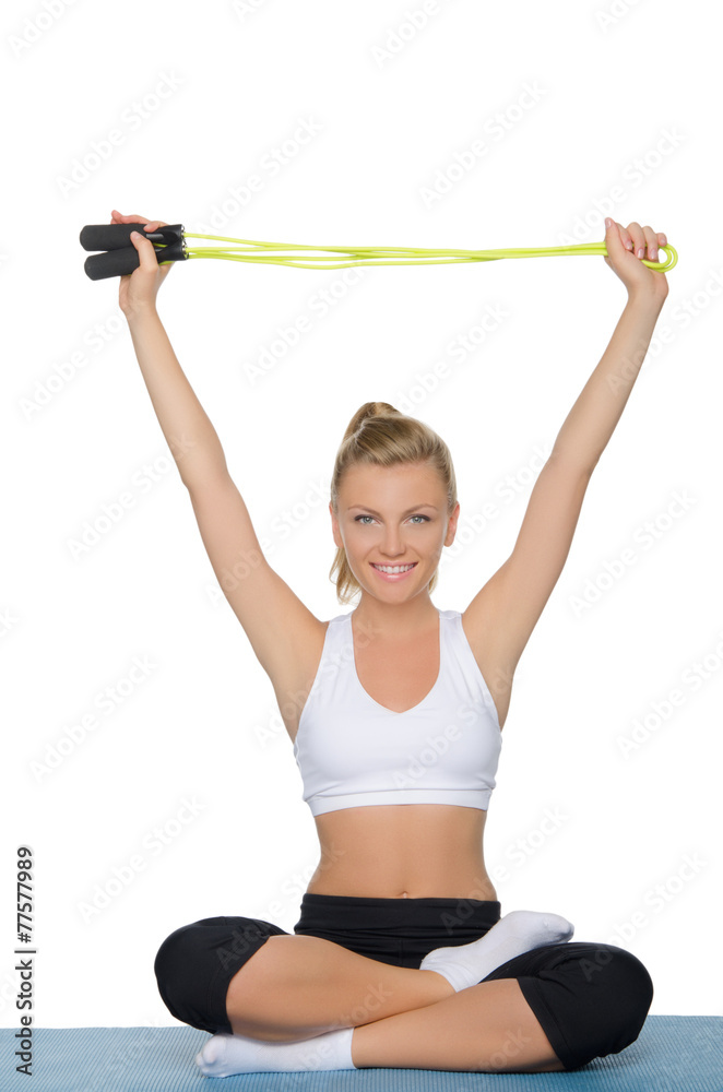 Smiling young woman with rope sitting on mat Smiling young woman with rope sitting on mat