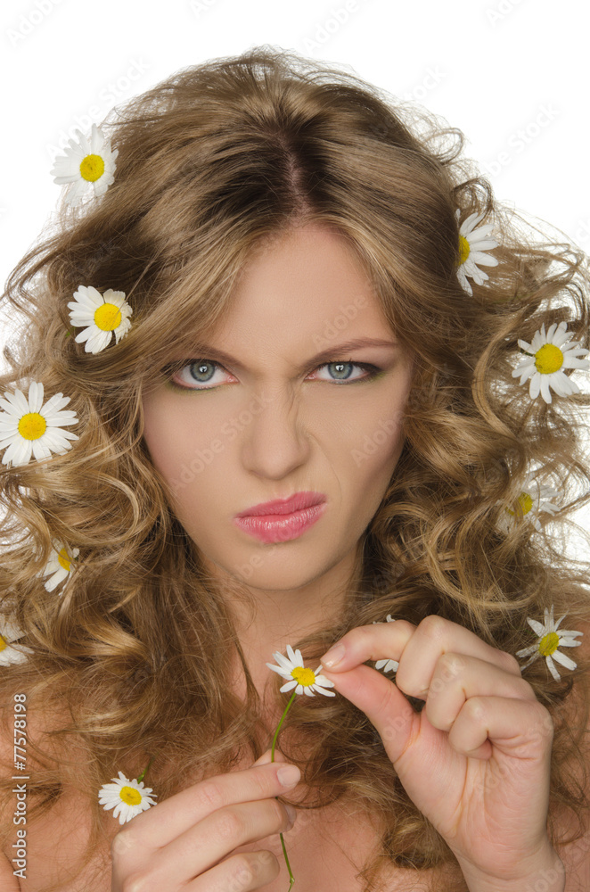 Fototapeta premium unhappy woman with daisies in hair takes petals