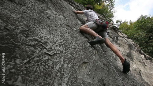 HD1080p: Man rock climbing in nature shot from below photo
