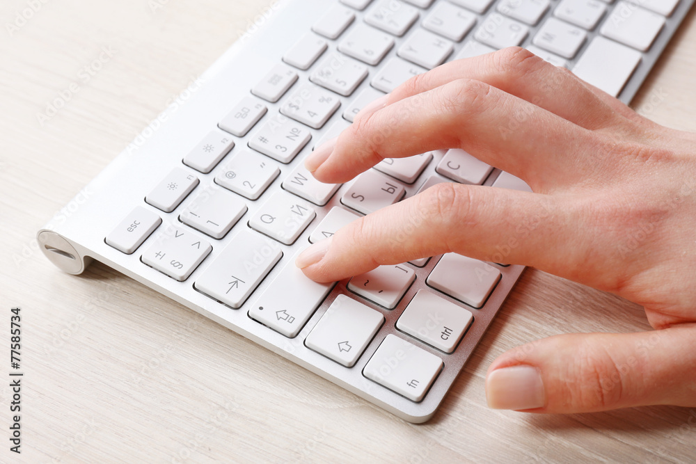 Female hand with keyboard on wooden desktop background Female hand with keyboard on wooden desktop background