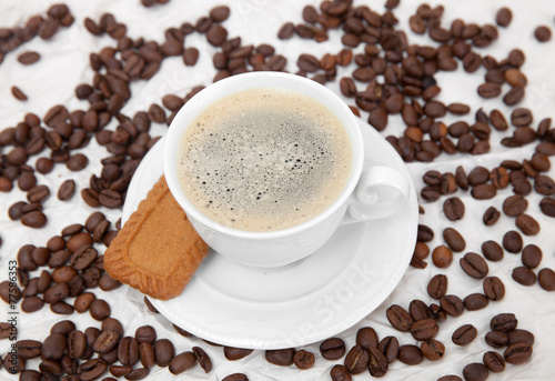 The white mug of espresso with cookie and scattered beans