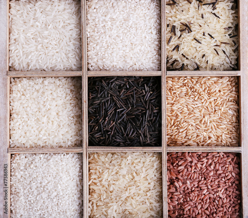 Different types of rice in box on wooden background