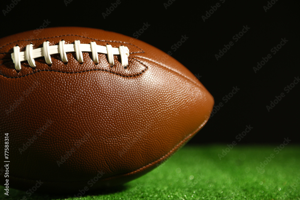 Obraz premium American football on green grass, on black background