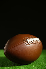 American football on green grass, on black background