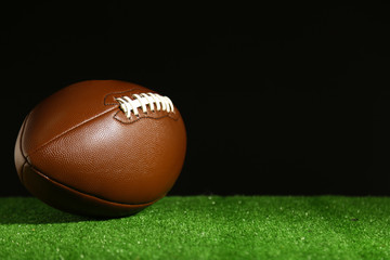 American football on green grass, on black background