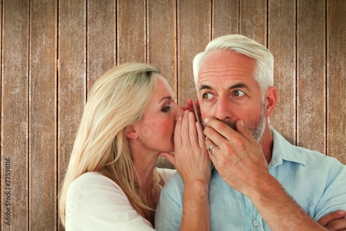 Composite image of woman whispering a secret to husband photo