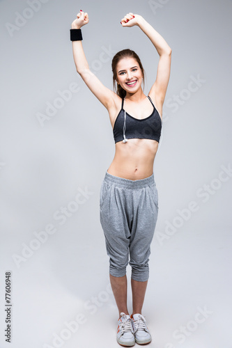 smiling sporty woman stretching leg over gray background