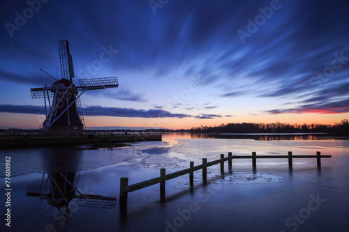 Traditional windmill at a lake during a cold sunset in winter.