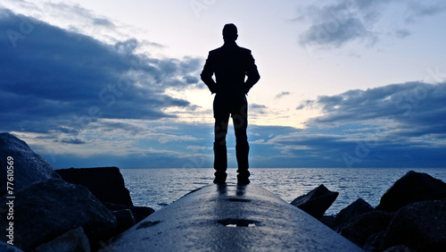 Hombre frente al mar esperando el atardecer azul photo