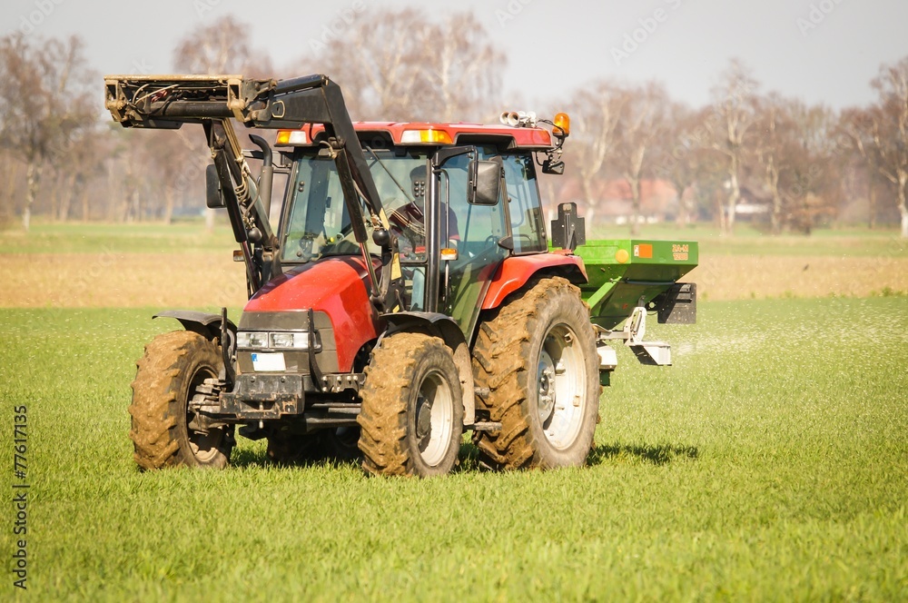 Naklejka premium Landwirt mit seinem Schlepper beim Dünger streuen