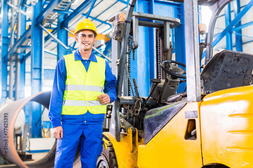 Forklift driver standing in manufacturing plant