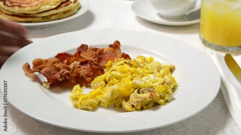 Table being set with pancakes, bacon and eggs Table being set with pancakes, bacon and eggs