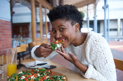 Young black woman eating vegetarian pizza