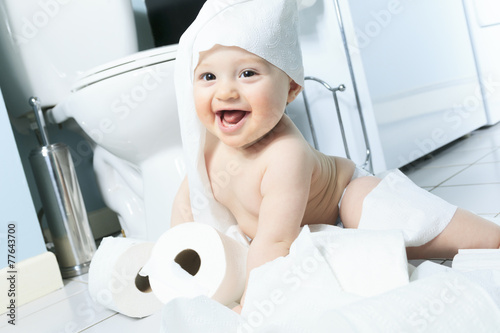 Toddler ripping up toilet paper in bathroom photo