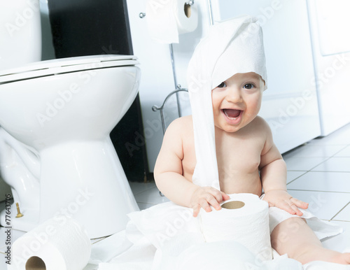 Toddler ripping up toilet paper in bathroom photo