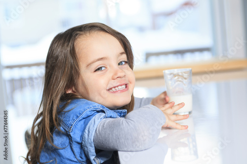 A Happy little child drinking milk on a kitchen
