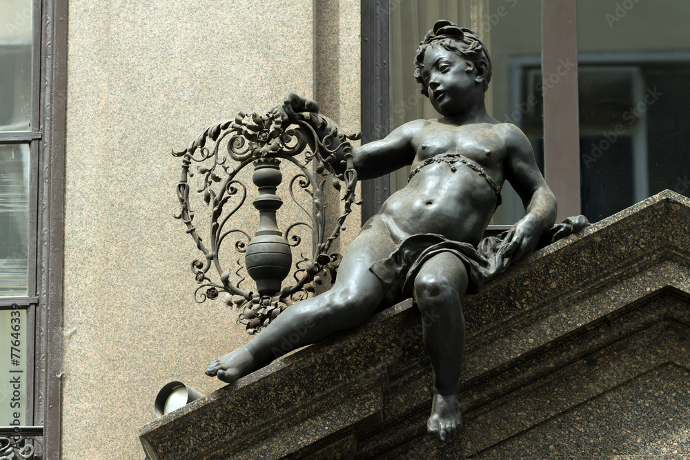 Naklejka premium Black sculpture of a boy with flowers on one of the roofs of Vie