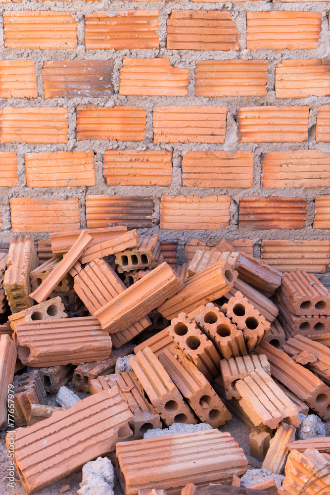 pile of bricks in construction site with brick wall background