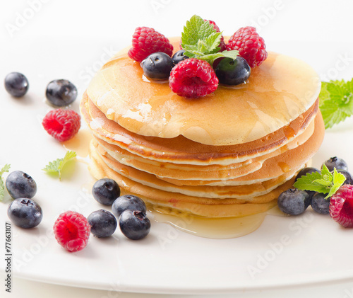 pancakes with raspberries and blueberies on  white plate