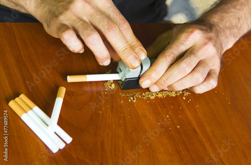 Man rolling cigarettes using fresh tobacco