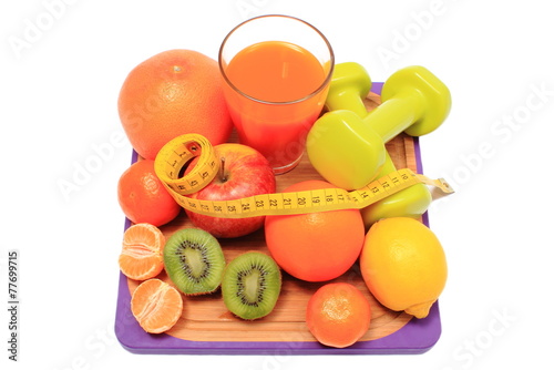 Fresh fruits, dumbbells, tape measure and glass of juice
