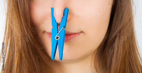 Portrait of young caucasian woman with Clothespin on her nose -